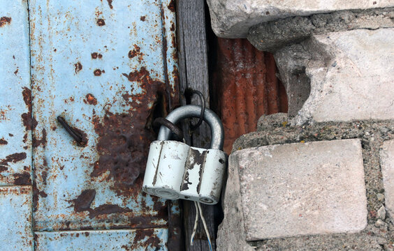 Rusty lock securing an old blue door in a weathered brick wall at a forgotten location
