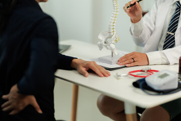 Doctor consulting with a patient suffering from back pain, offering guidance and treatment options...