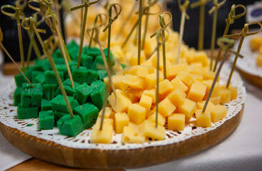 Colorful cheese platter featuring green and yellow cheese cubes ready for tasting at a gathering