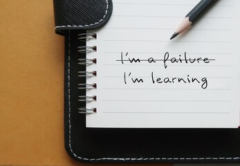 Notebook with text  I'M A FAILURE crossed off to  LEARNING, replace negative self-talk with positive thoughts, learn to build self-acceptance and embrace failure as part of growth and learning