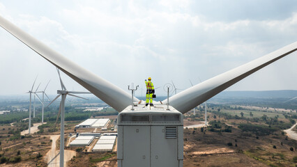 Electric engineer wearing Personal protective equipment working on top of wind turbine farm. © SHUTTER DIN