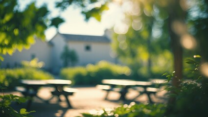 Naklejka premium Blurry Background of a Peaceful Community Park featuring a Play Area Surrounded by Lush Greenery and Picnic Tables on a Sunny Day in Early Summer. Blurred Background for Design Projects.