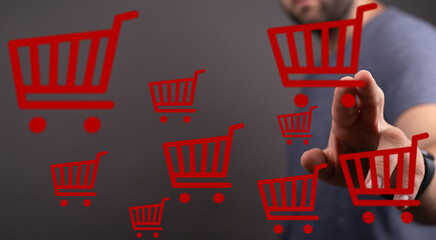 Image depicts a man interacting with virtual shopping carts, representing online shopping and...