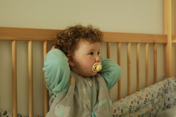 Sweet toddler peacefully resting in crib. Soft lighting and neutral colors.