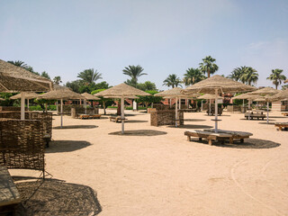 Tranquil beach scene with straw umbrellas and lounge areas under a clear sky. Perfect for conveying relaxation, summer vacations, and resort getaways Safaga, red sea Egypt