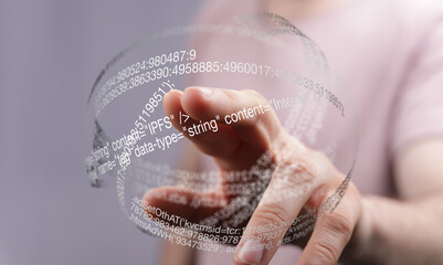 Hand interacting with a transparent digital sphere showing data and code.