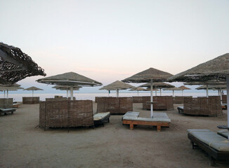 Sunset over beach scene with straw umbrellas and lounge areas under a clear sky. Perfect for conveying relaxation, summer vacations, and resort getaways Safaga, red sea Egypt