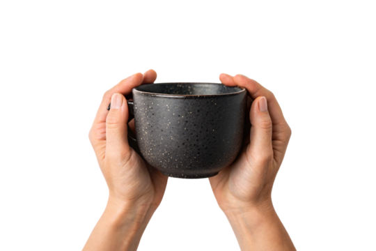 Two hands cupping dark ceramic bowl with speckled texture creating protective gesture around handmade pottery, isolated on a transparent background