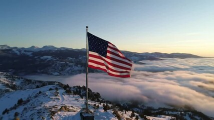 American flag billows proudly atop a snow-covered mountain peak, overlooking a sea of clouds at sunrise. - Powered by Adobe