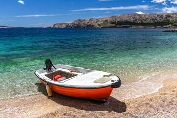 Jablanova Beach, orange fishing boat pulled up on the shore of an empty beach against the backdrop of the Adriatic Sea
