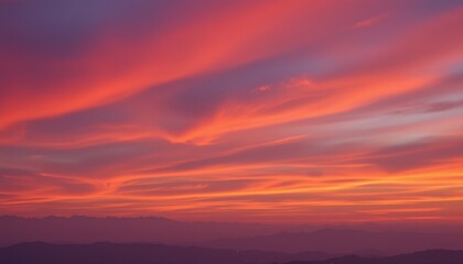 Vibrant sunset sky over distant mountain range Layered clouds display warm orange and pink hues