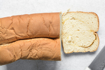 Overhead view of bread being sliced, process of making bread pudding