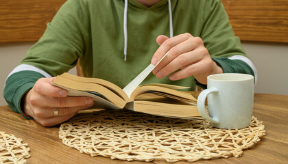 A man is sitting in a cafe and reading a book