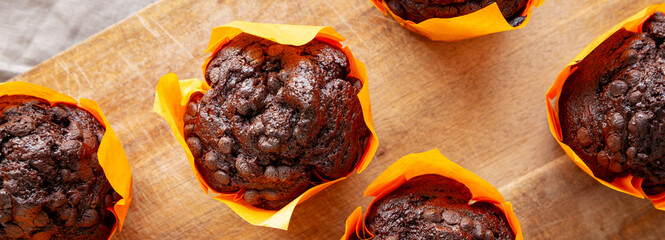 Homemade Chocolate Chip Muffins on a wooden board, top view.