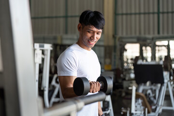 Weightlifting. Happy man lifting dumbbell in gym.