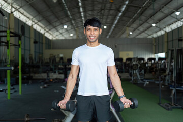 Fitness and Strength Training. Young man lifting dumbbells in gym for strength and wellness.