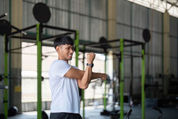 Strength and Flexibility. Young man stretching after workout in gym.
