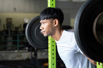Strength Training. Man performing squat exercise with barbell in gym.