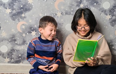 An older sister reads a book to her little brother — a moment of family warmth and early childhood development.