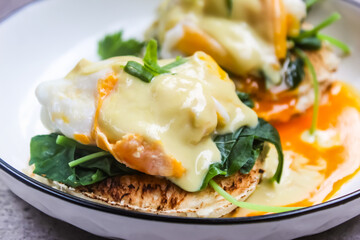 close up of eggs benedict and spinach on a plate as a breakfast menu