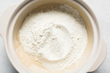 Overhead view of homemade pretzels dough being mixed in a bowl, top view of soft pretzel dough on a white background