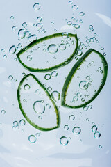 Three aloe vera slices floating in clear water surrounded by air bubbles, representing freshness, hydration, and natural skincare