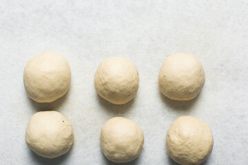 Overhead view of homemade pretzels dough being shaped on a white countertop, process of making soft pretzel