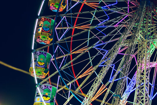 Ferris wheel at night with colorful lights. Colorful fairground attraction.