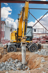 Construction site featuring a heavy excavator drilling into rocky ground under a clear sky
