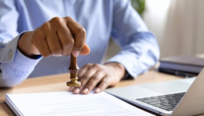 close-up shot of a hand applying a legal stamp to a contract in an office, signifying the final approval and authentication of important business documents.