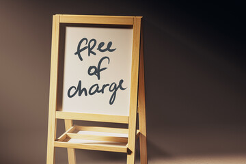 Wooden sign that says Free of Charge is on a wooden easel stand. The sign is black on white and has a simple, straightforward message. 3d render