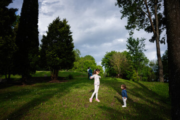 Children playing outdoors in a green park surrounded by tall trees