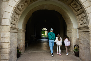 Family walking through historic stone archway towards a bright garden area