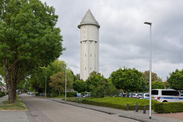 Fototapeta premium The prominent water tower of Meerkerk, Netherlands, framed by lush green trees. This historic landmark, built in 1936, is a part of the local infrastructure, a striking feature of the Dutch landscape.