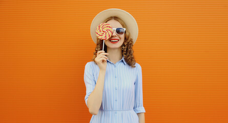 Summer portrait of happy young woman holding colorful lollipop, cheerful girl smiles in tourist hat
