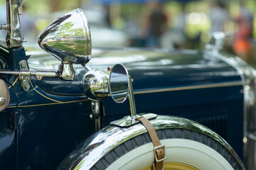 Chrome spotlight, round side mirror and whitewall spare wheel with leather strap on a dark blue...
