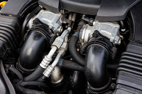 Modern car engine bay, highlighting various mechanical components, hoses, and wiring