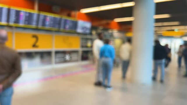 People waiting to greet passengers stand at arrival gate 2 at Warsaw Chopin Airport (WAW), Poland. Passengers arriving by plane exit with their luggage. Out of focus.