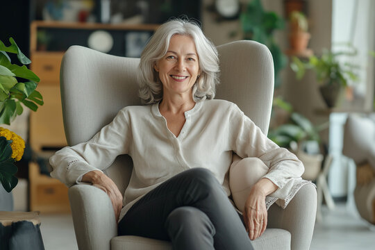 Happy elegant senior woman sitting in living room at home. Relaxation, wellbeing concept