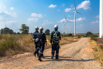 Rear view group of wind turbine engineers working in wind turbine field surveying environment impact