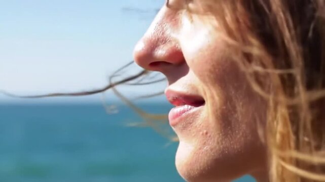 Close-Up Profile of a Woman with Wind-Blown Hair at the Beach. Serene Beach Scene with a Woman's Face in the Sun. Natural Beauty Wind-Blown Hair Against a Blue Sky and Ocean. Peaceful Moment 