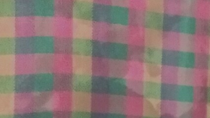 A close-up image showcases a soft, muted pastel plaid fabric texture. The colors blend subtly, creating a calming and gentle visual effect.