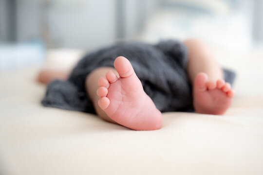 Soft baby feet resting on a cozy bed in a peaceful and tender home atmosphere