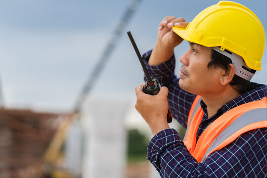 Construction Worker Communicating with Walkie-Talkie, On-Site Supervisor with Two-Way Radio and Safety Gear, Engineer or Foreman Listening to Instructions at Construction Site