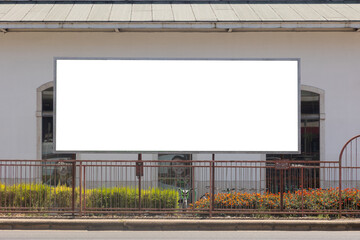 Blank horizontal billboard in Lisbon, Portugal, mounted on a building facade with flowers and a sidewalk in front. Ideal for advertisement or mockup use in urban settings.