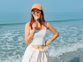 Young woman with colorful lollipop and orange hat enjoy the beach.