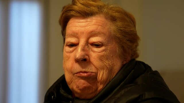 Elderly woman enjoying chips at home in the evening light, closeup shot