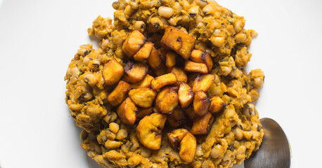 Overhead view of nigerian fried beans and fried plantain on a white plate, top view of nigerian stewed beans and plantain on a white background