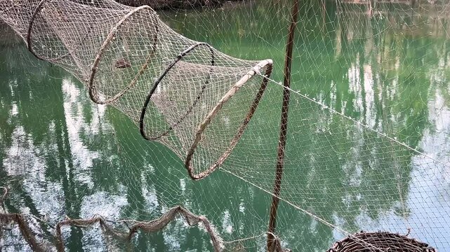 Antique fishing nets are hung on the pier against the backdrop of the lake.