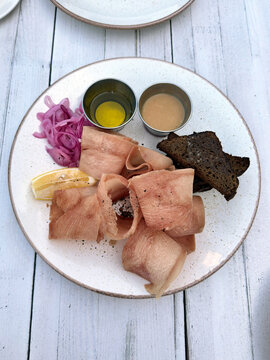 Traditional Baltic dish stroganina from bonito with rye croutons, pickled onions, sauce and butter